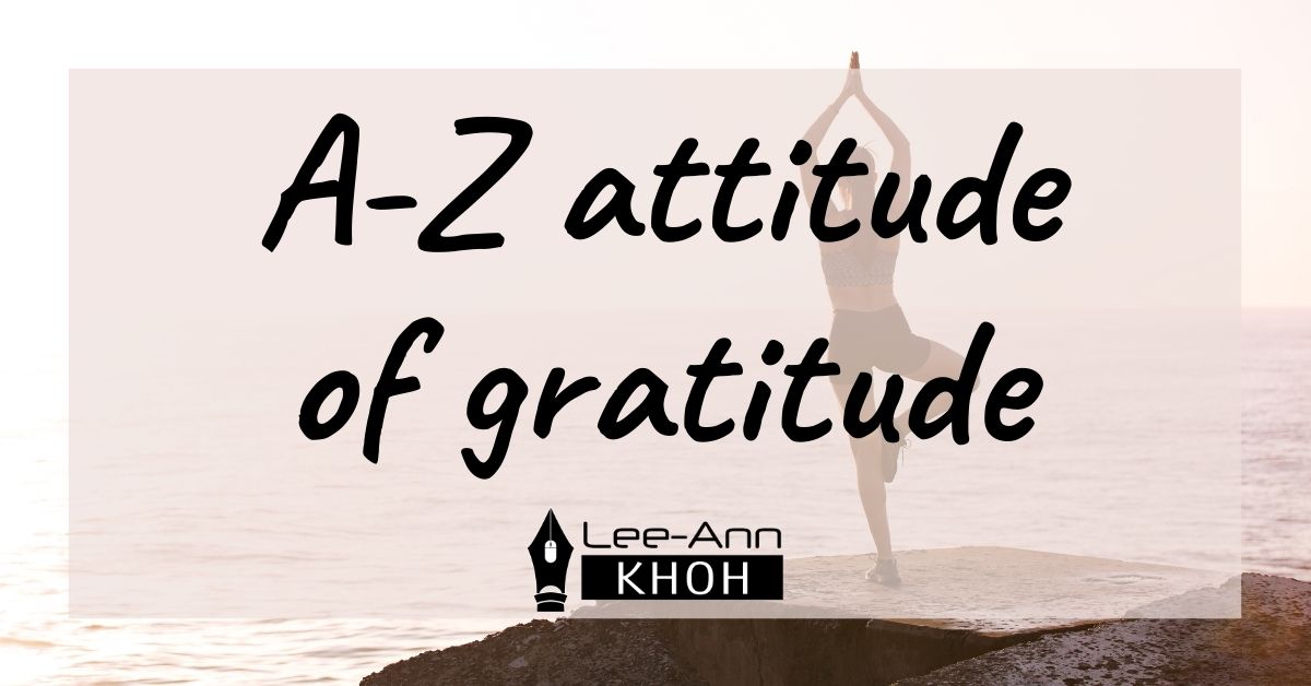 Text reads: A-Z attitude of gratitude. Background contains a person practising yoga on a rock overlooking the ocean.