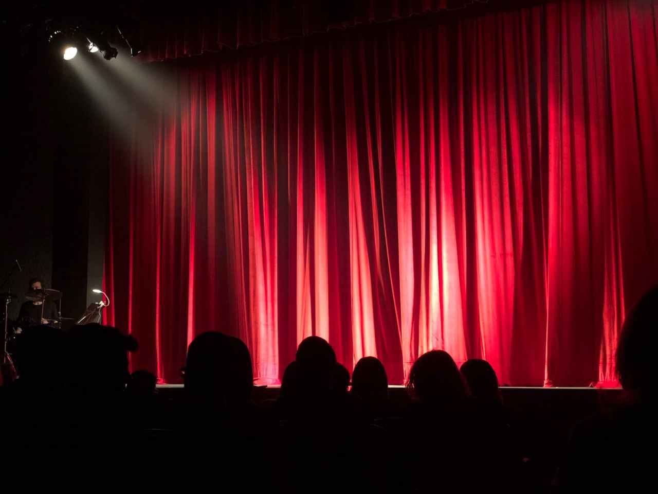 Silhouettes of people at the theatre with curtains closed.