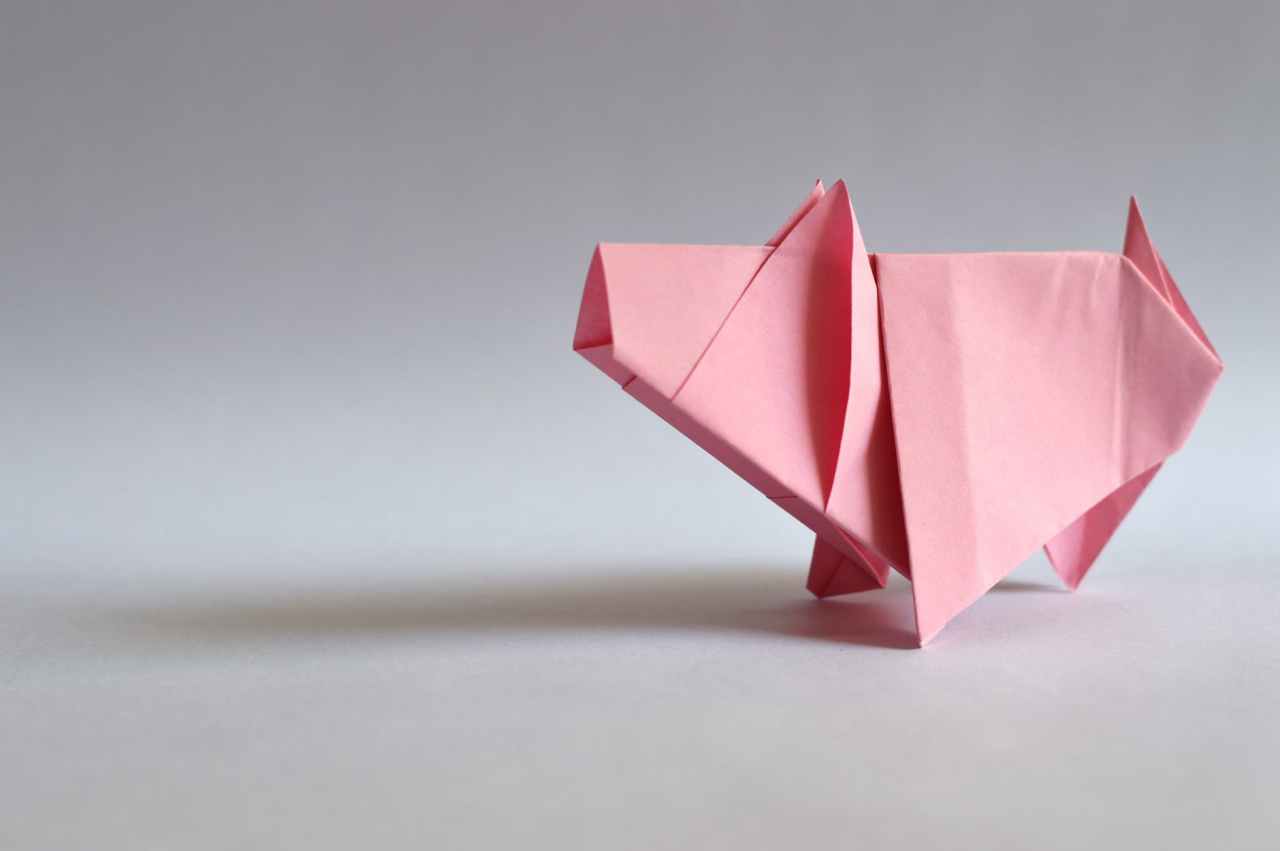 Origami pig folded with pink paper.
