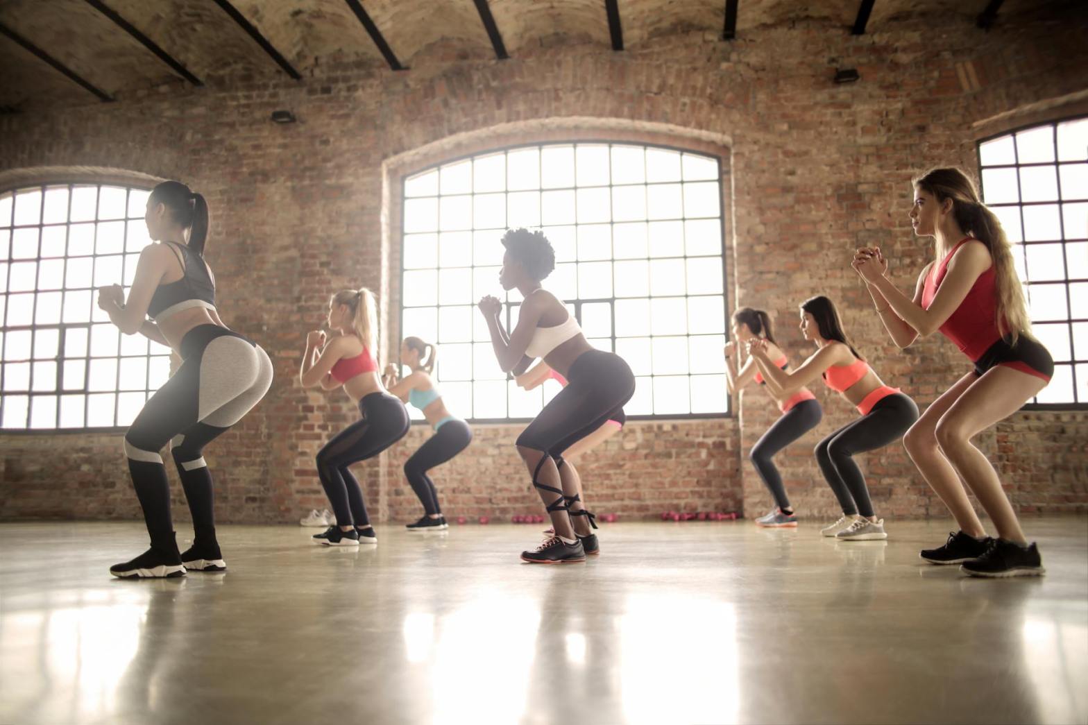 Group of women doing squats in an exercise class.