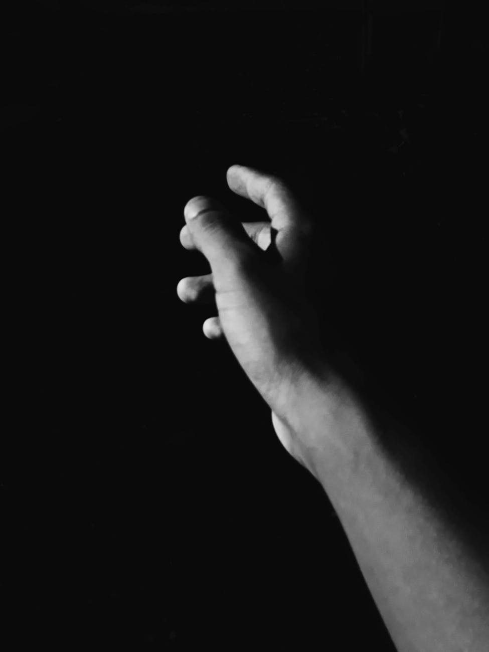 A hand reaching out against a black background.